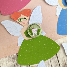 Load image into Gallery viewer, A ginger haired tooth fairy with green glasses and a green dress. She is holding a I lost my first tooth badge which also has a cute tooth with wings and a crown.