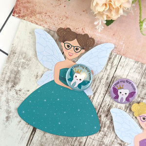 A brown hair tooth fairy wearing a jade dress. She is holding a badge that features a tooth with wings, wearing a crown.