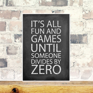 Chalkboard print with the words 'it's all fun and games until someone divides by zero' on a brick background