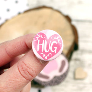 Close up of pink 'HUG' badge