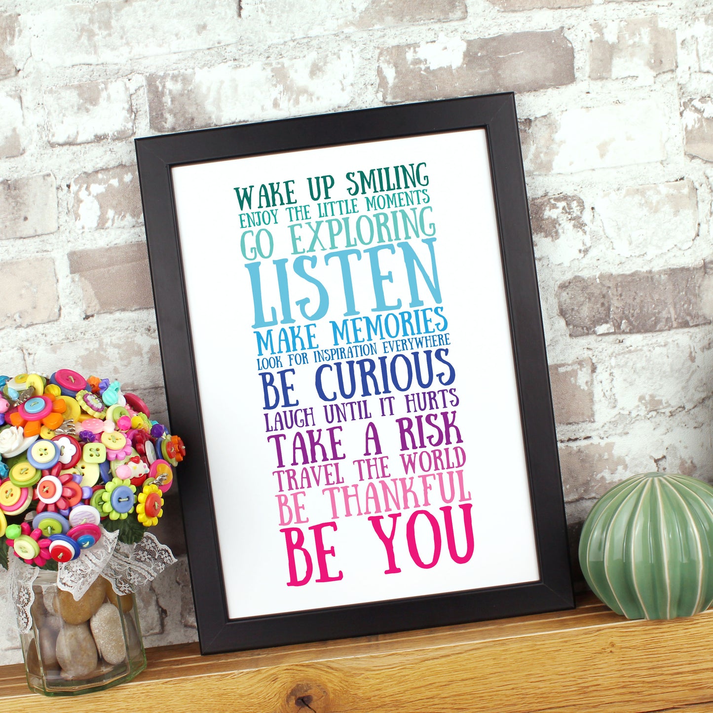 Inspirational print in a black frame on a wooden shelf