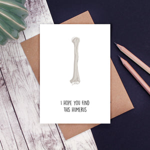 A white card with a human humerus bone and the words 'I hope you find this humerus'